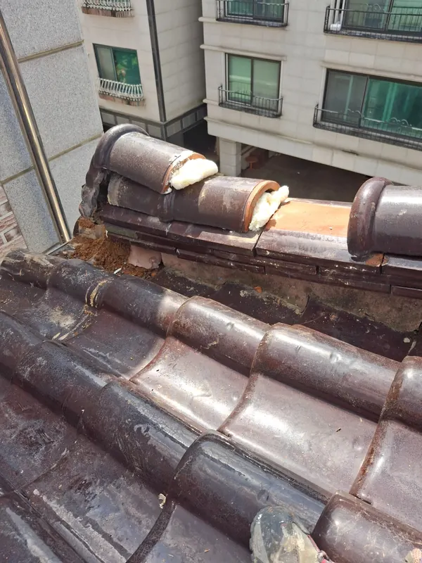 기존 기와를 맞추며 용마루 주변을 다시 고정하는 과정